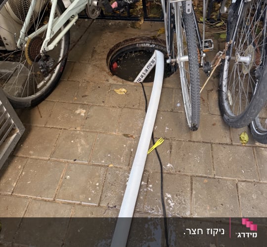 צינור מחובר לפתח ביוב ליד אופניים